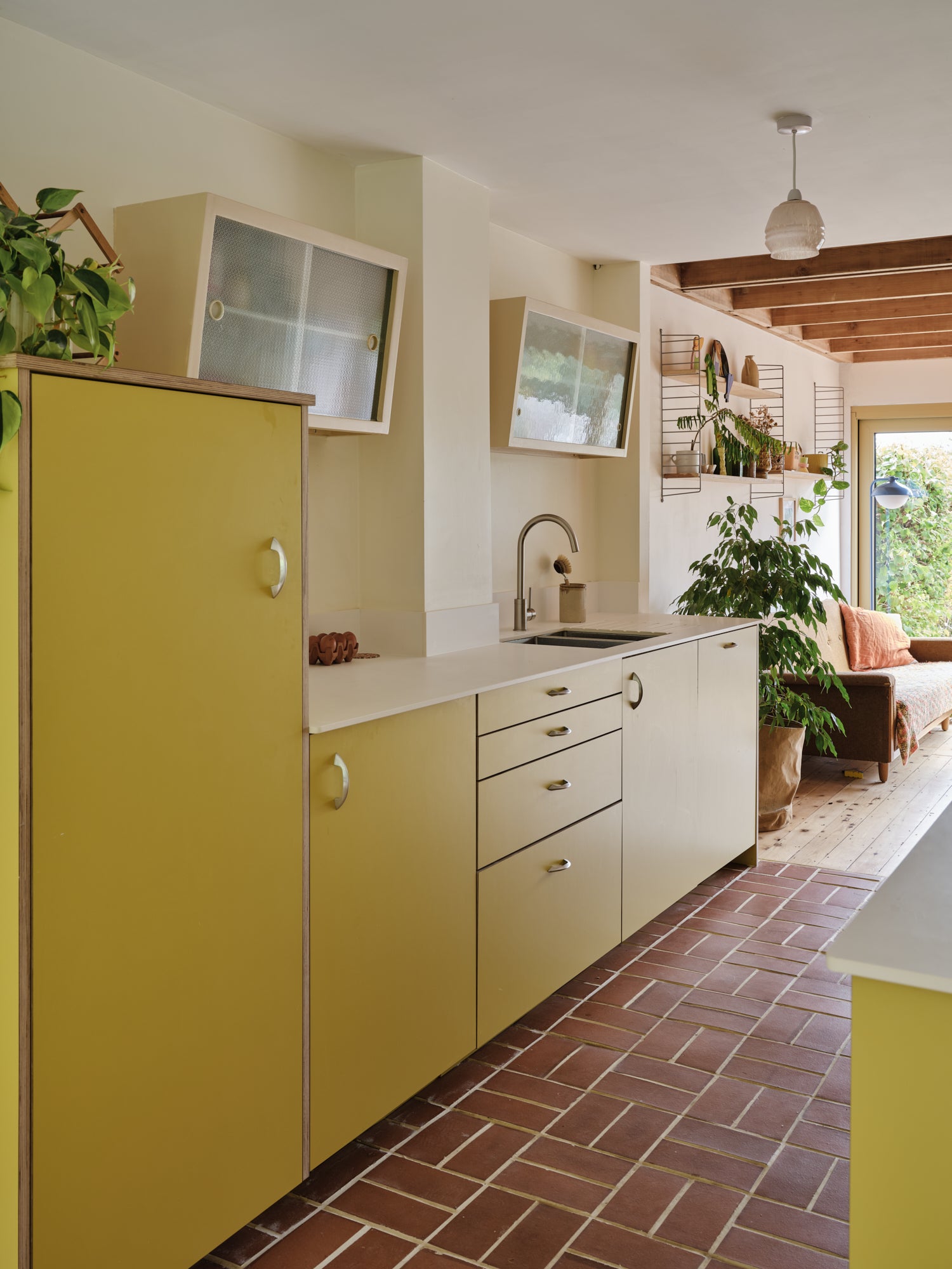 Modern kitchen with yellow cabinets and a brick floor